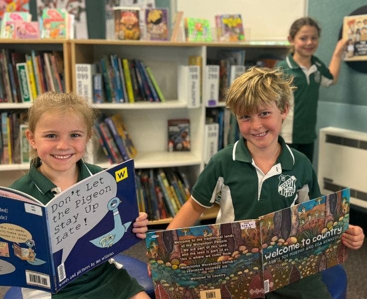 Two children reading books in our library.