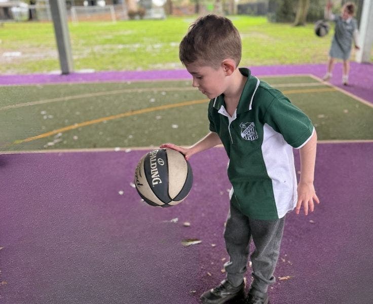 A student bouncing a ball at our basketball court.