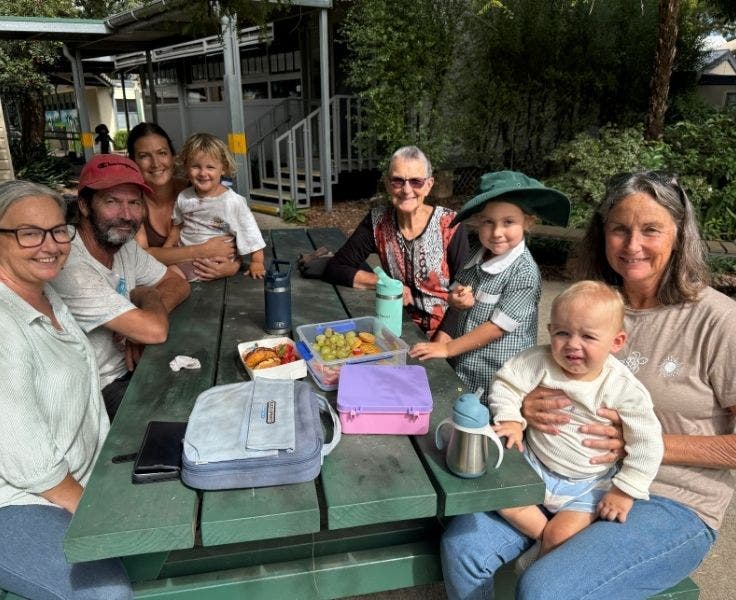 A family sitting together at a picnic table having morning tea.