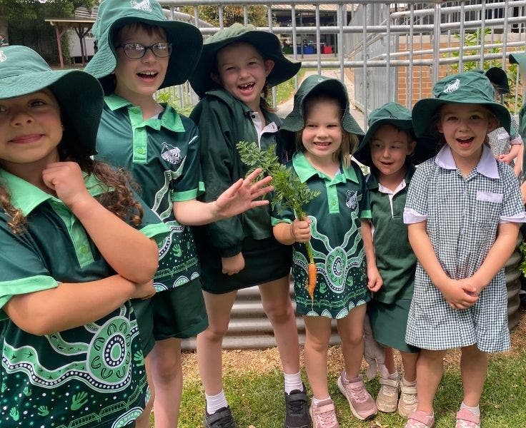Six children at our garden, one student is holding up a carrot.