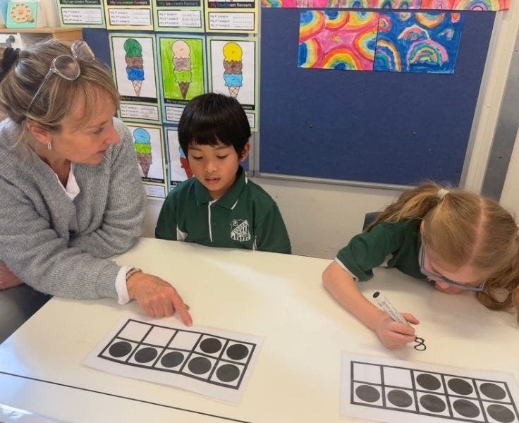 Two students completing a math activity and a SLSO providing support to one of the students.