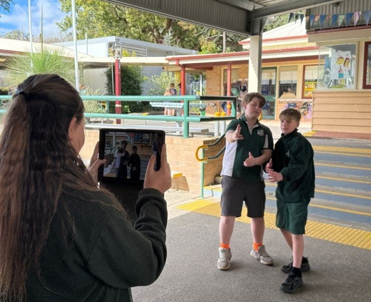 Two students being filmed by another student.