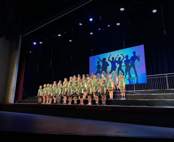 Stage 2 and 3 standing on the stage for their choral performance.