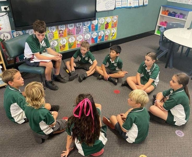 Group of students sitting in a circle while the peer support group leader leads an activity.