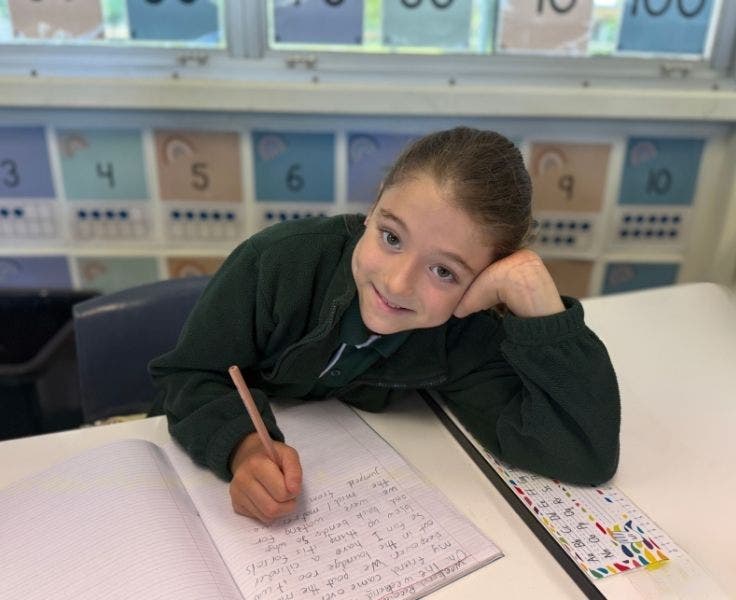 Student writing at their desk.