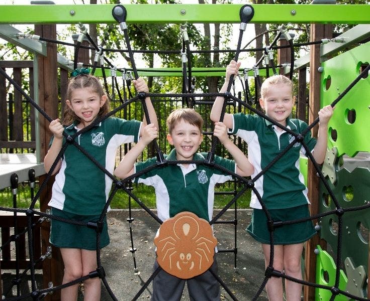 Three children climbing on play equipment.